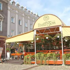 Zadaszony ogródek restauracji Brax'Ton z widoczną kawiarnią w tle.