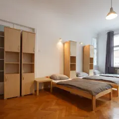Pokój wieloosobowy z kilkoma łóżkami, szafkami i oknami. Idealne miejsce, gdzie szukać tanich noclegów.