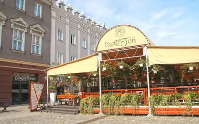Zadaszony ogródek restauracji Brax'Ton z widoczną kawiarnią w tle.