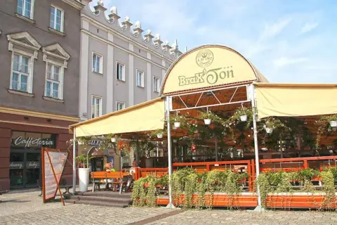 Zadaszony ogródek restauracji Brax'Ton z widoczną kawiarnią w tle.