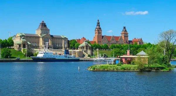 Widok na port w Szczecinie z budynkami muzealnymi i statkiem na wodzie.