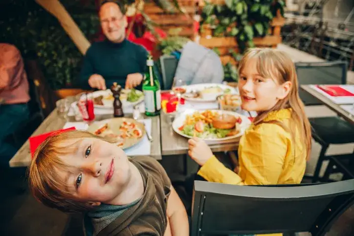 rodzina z dziećmi jedząca obiad w restauracji z kącikiem zabaw