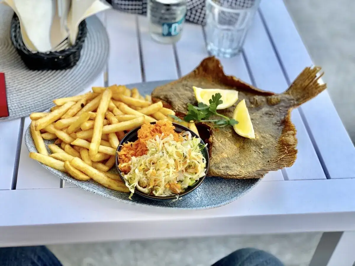 świeża smażona ryba z frytkami i sur&oacute;wką w restauracji nad morzem