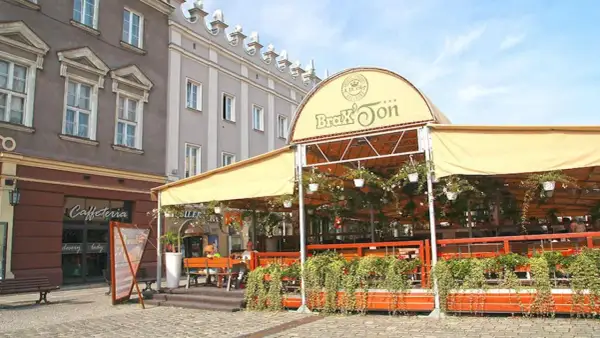 Zadaszony ogródek restauracji Brax'Ton z widoczną kawiarnią w tle.