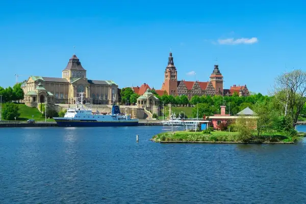 Widok na port w Szczecinie z budynkami muzealnymi i statkiem na wodzie.